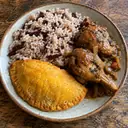 Illustrative photo: rice and beans, Caribbean chicken and a patty on a wooden table
